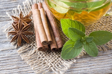 Cup of tea with fresh mint leaves and cinnamon anise on a wooden background. Copy space.