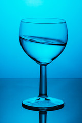 Water splash in wine glass on blue background