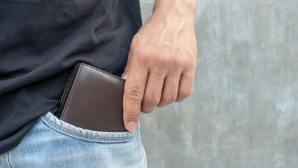 Men hold a brown wallet from a jeans pocket. - 214934824