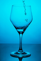 Water splash in wine glass on blue background