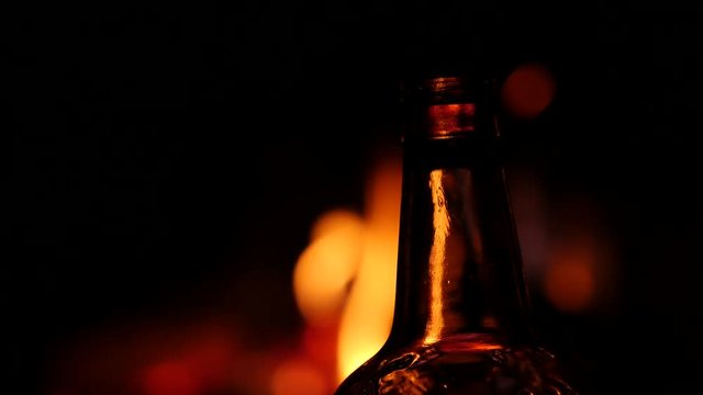 beer bottle on a fire background in a dark. flame game on brown glass. 4K