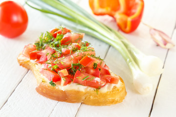 Bruschetta with fresh tomatoes and cheese on a background of fresh vegetables on white boards. Close-up