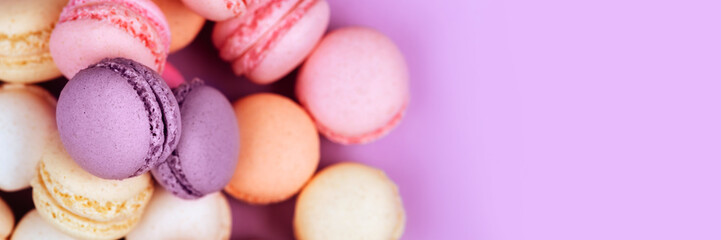 The row of colorful macarons on pink background.