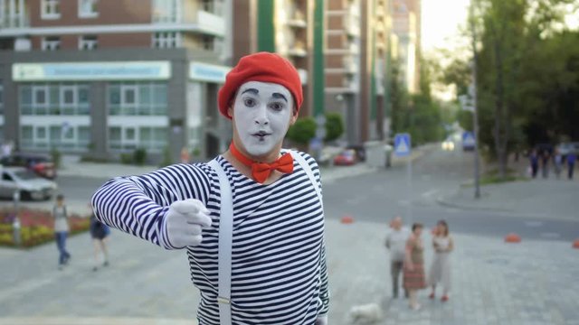Mime in red beret point his finger on camera