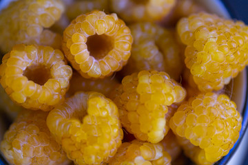 fresh yellow raspberries in a ceramic bowl on a black wooden background