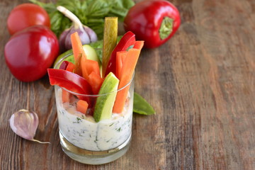Various fresh vegetables in a glass with yogurt sauce, copy space
