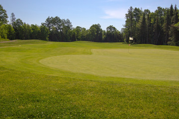 Fototapeta na wymiar The 18th Hole. Putting green and fairway at the 18th hole on a sunny summer day.