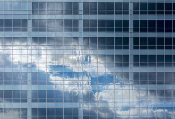 Reflection of the sky and clouds in the Windows of a multi-storey glass building