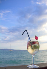 Cocktail with champagne and strawberries on a background of sea and sky. Vertical