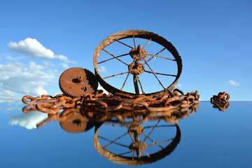 Rusty scrap-iron heap on mirror and clouds