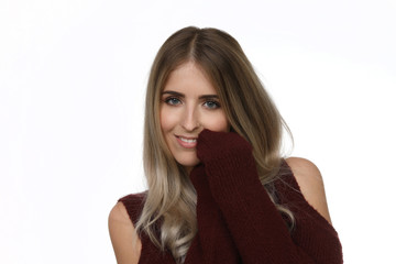 Hübsche junge blonde Frau mit Pullover bekleidet lächelt