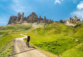 Alpine activities in Dolomites,Italy. Mountainbiking uphill on the Mountain Road in Dolomites Mountains. Rocky Mountains Ridge in the background. Cycling with bikes on track, Cortina d'Ampezzo