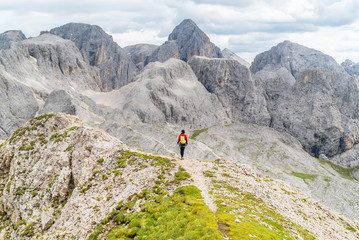 Hiker on the ridge of Dolomites Mountains in Alps, Italy. Via ferrata trail. Peole on the rocky...