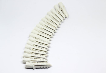 Row of white plastic dowels on white background.