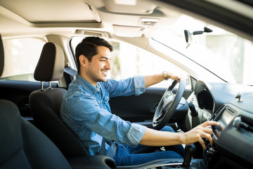 Hispanic man using a touchscreen while driving his car