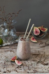Healthy smoothie with fresh figs, banana and honey in glasses jar on a wooden background