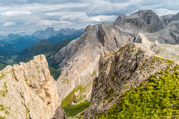 Fototapeta premium Hiker on the ridge of Dolomites Mountains in Alps, Italy. Via ferrata trail. Peole on the rocky mountains path. Travel in Dolomites. Adventure in the mountains. Mountain climber on an exposed ledge