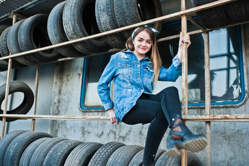 Young hipster girl in jeans jacket and head scarf at tire fitting zone.