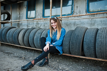 Young hipster girl in jeans jacket and head scarf at tire fitting zone.