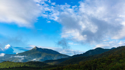 Beautiful green mountain peak landscape on a blue sky with some clouds