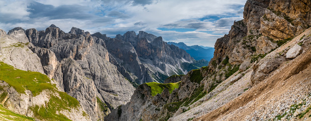 Fototapeta na wymiar Landscape of Dolomites with green meadows, blue sky, white clouds and rocky mountains. Italian Dolomites landscape. Beauty of nature concept background. The valley below. Evening panoramic view. 