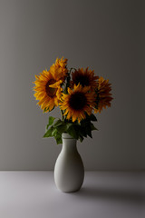 decorative bouquet of yellow sunflowers in vase, on grey