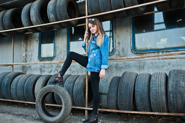 Young hipster girl in jeans jacket and head scarf at tire fitting zone.