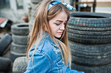 Young hipster girl in jeans jacket and head scarf at tire fitting zone.