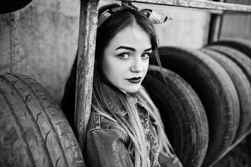 Young hipster girl in jeans jacket and head scarf at tire fitting zone.