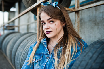 Young hipster girl in jeans jacket and head scarf at tire fitting zone.