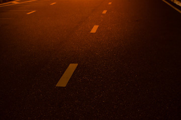 the night avenue with road markings and headlights of the approaching cars