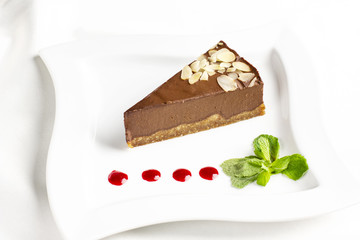 The piece of chocolate souffle cake with mint and jam drops on white plate
