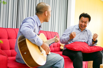 Obraz premium Two asian guys are playing guitar, music instrument for happy and smile feeling.