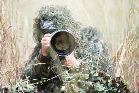 Photographer in ghillie suit hiding in forest to take wildlife photo for education