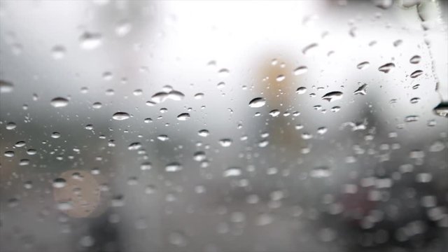 Rain falling on a windshield with windshield wipers in slow motion