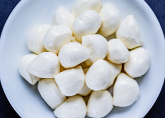 mozzarella balls in plate on black background, top view. Flat lay. Food concept.