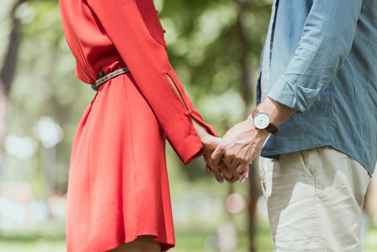 cropped image of couple holding hands in park