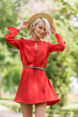 Obraz premium stylish attractive girl in red dress and straw hat posing in park