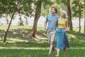 Fototapeta premium young couple walking with badminton rackets and shuttlecock to play in park