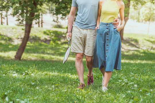 cropped image of couple walking with badminton rackets and shuttlecock to play in park