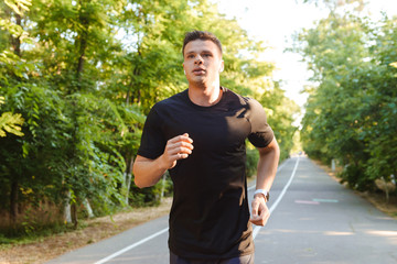 Confident young shirtless sportsman in earphones running