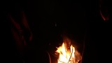 Silhouettes of young people singing songs with guitar sitting by the campfire