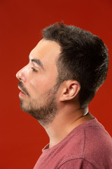 Obraz premium Beautiful man looking suprised and bewildered isolated on red