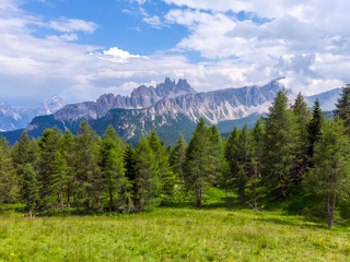 Landscape of Dolomites with green meadows, blue sky, white clouds and rocky mountains. Italian Dolomites landscape. Beauty of nature concept background. The valley below. Evening panoramic view. 