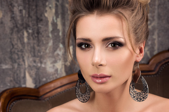 Closeup portrait of beautiful young woman with evening make-up. Large earrings and hairstyle