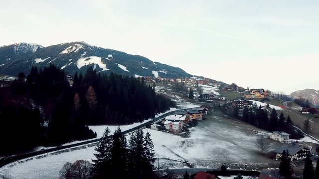 Ascending drone shot above a small Austrian Ski town in a beautiful snow-capped mountain scene.