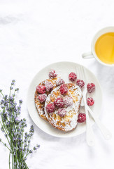 French toast with raspberry, powdered sugar and green tea for cozy breakfast. On a light background, top view. Flat lay