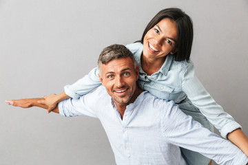 Portrait of joyful caucasian people man and woman in basic clothing smiling and hugging together, isolated over gray background