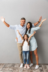 Full length photo of beautiful caucasian family woman and man with little girl smiling and hugging...