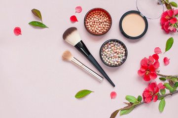 Obraz na płótnie Canvas Various cosmetic products for make-up with red flowers on a pink background with copy space. Makeup Accessories Top view Flat Lay. Powder Rouge Eyeshadow Corrector Brushes